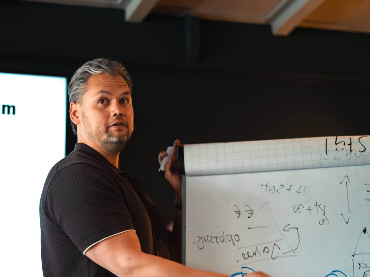 Mitch legt uit bij het whiteboard tijdens een mastermind-dag