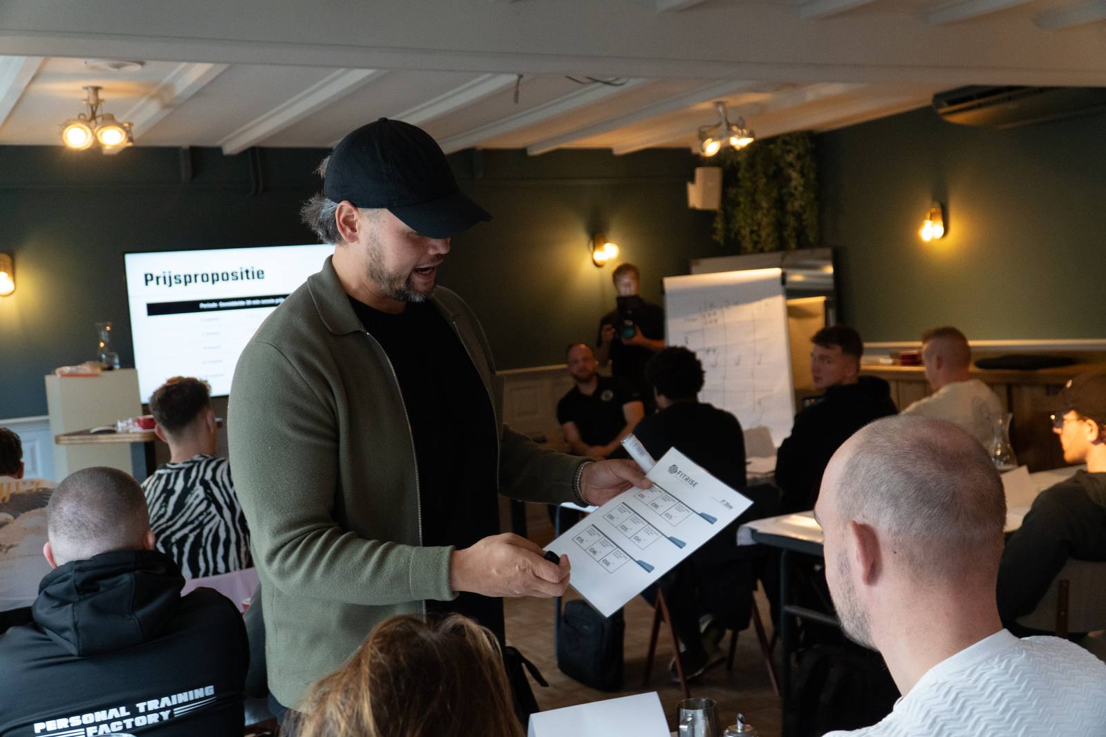 Mitch deelt het Prijspropositie-werkblad uit tijdens een mastermind-sessie